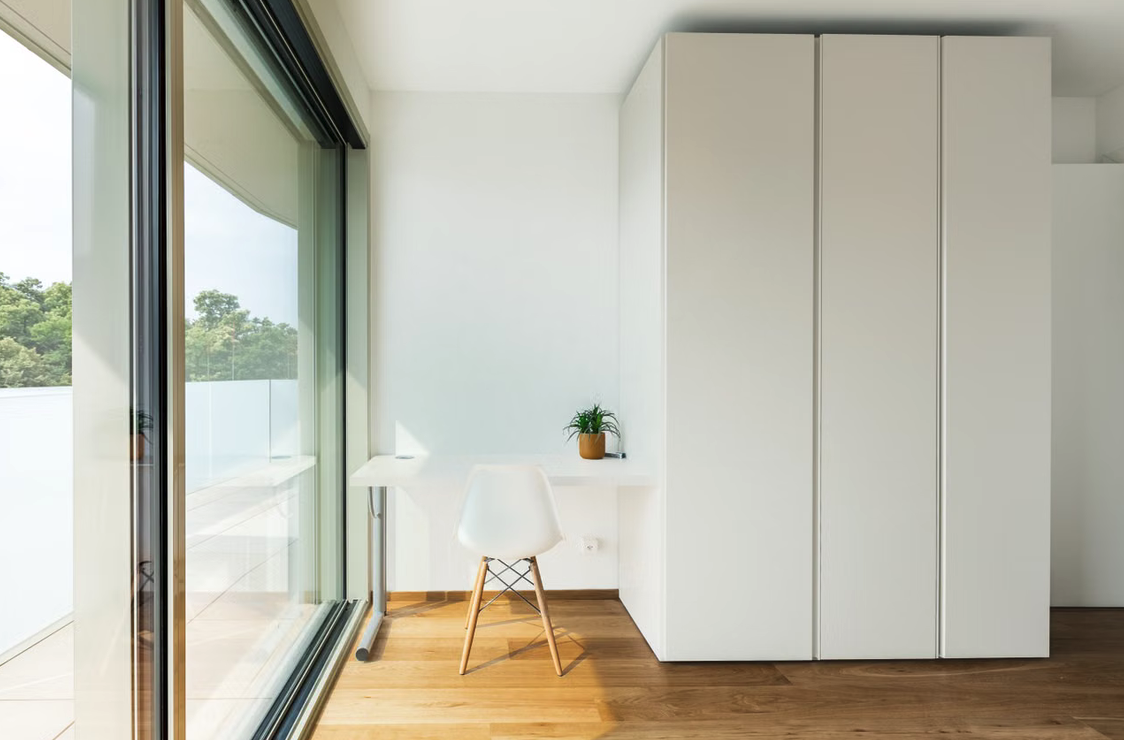 Weißer Kleiderschrank der an einer Außenwand steht.
